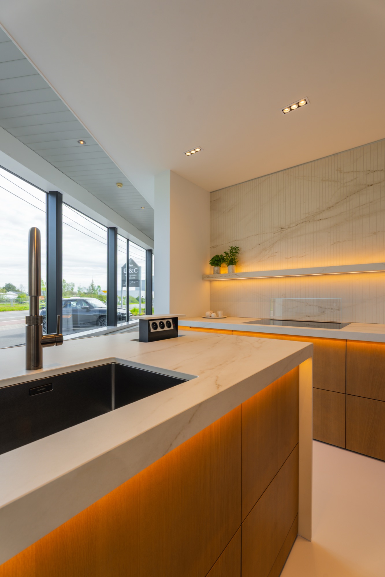 Keuken met marmerlook werkblad, spoelbak en warme ledverlichting bij het raam